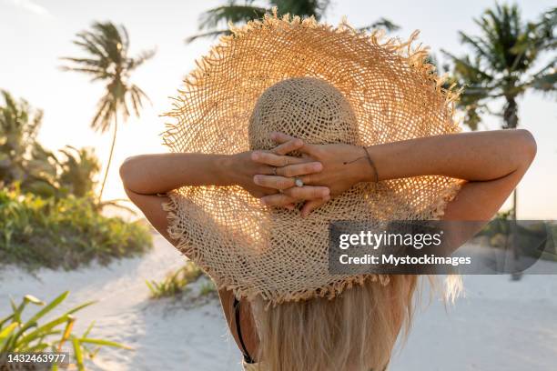 female relaxing on tropical beach at sunset - straw hat stock pictures, royalty-free photos & images