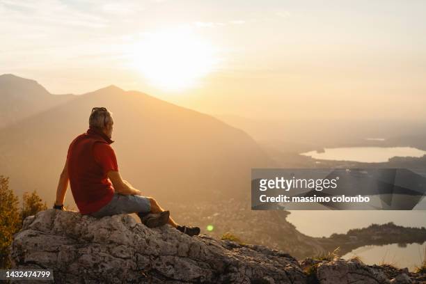 man sitting on top of the hill enjoying the sunset - rebirth stockfoto's en -beelden