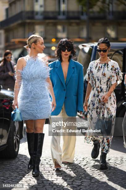 Justyna Czerniak wears black earrings, a pale blue feather halter-neck / sleeveless / short dress, a blue shiny metallic leather handbag, black shiny...