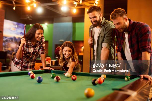 grupo de amigos se divertindo enquanto jogava sinuca em um salão de sinuca local - azar - fotografias e filmes do acervo