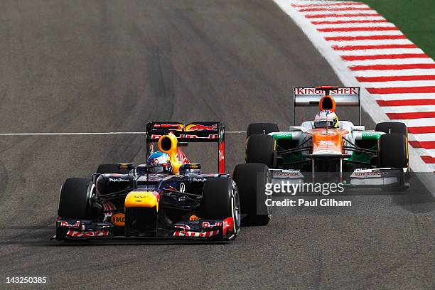 Sebastian Vettel of Germany and Red Bull Racing and Paul di Resta of Great Britain and Force India drive side by side during the Bahrain Formula One...
