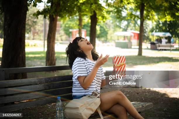 portrait of a girl having fun eating popcorn outdoors - catching food stock pictures, royalty-free photos & images