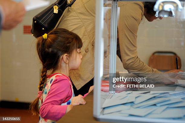 French girl looks at her mother preparing to cast her ballot at a polling station, on April 22 in La Marsa near Tunis, as part of the 2012 French...