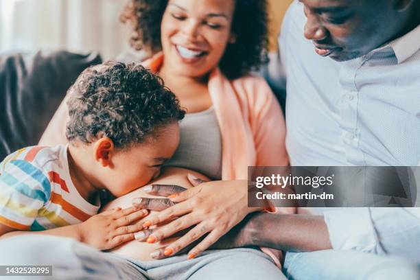 pregnant woman with husband and son at home - belly kissing stock pictures, royalty-free photos & images