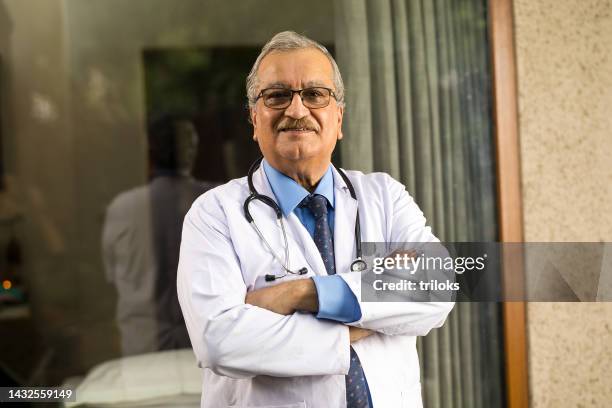 medico maschio anziano che guarda la telecamera - india doctor foto e immagini stock