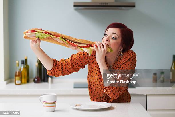 portrait of woman eating giant baguette - woman sandwich stock pictures, royalty-free photos & images