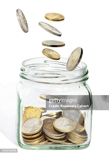 euro coins tumbling into a jar - pièce de monnaie d'euro photos et images de collection