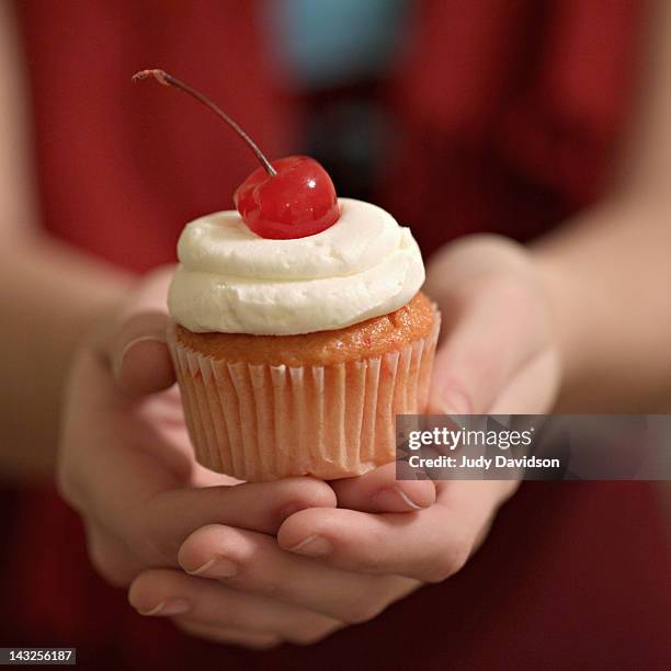 hands holding cherry cupcake - sahne stock-fotos und bilder