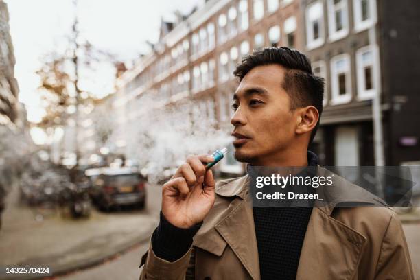 japanese man vaping in the street - electronic cigarette stockfoto's en -beelden