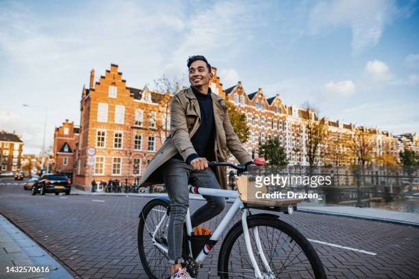 tausendjähriger asiatischer tourist in der stadt mit fahrrad - commuter man europe bike stock-fotos und bilder