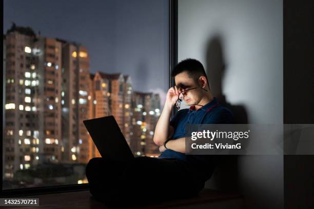 uomo asiatico che lavora a casa tardi con il laptop di notte - nuova normalità concetto foto e immagini stock