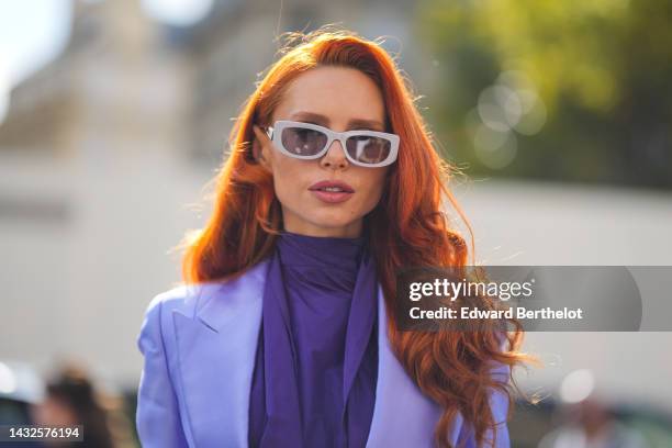 Guest wears gray plastic sunglasses from Prada, a dark purple turtleneck blouse, a purple blazer jacket, outside Giambattista Valli, during Paris...