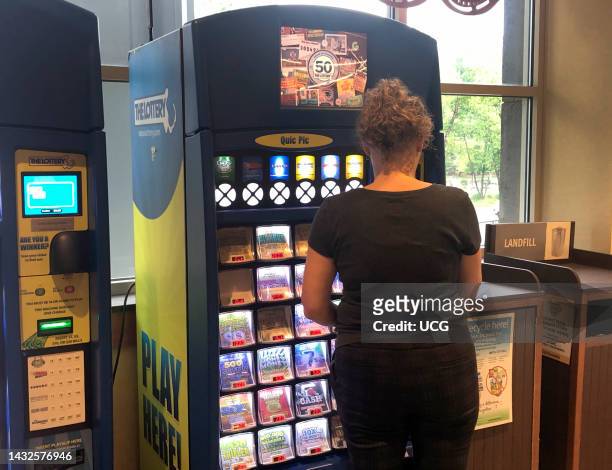Woman purchasing scratch off Lottery Tickets at Quic Pic machine in Whole Foods, Boston, Massachusetts.