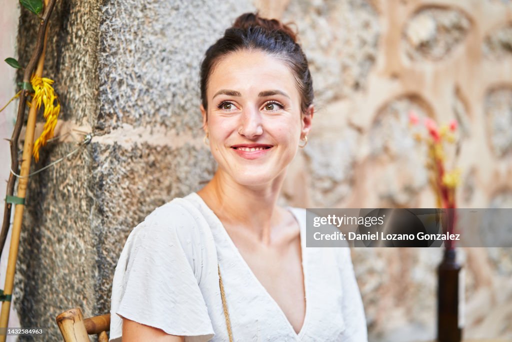 Joyful woman smiling while sitting at an outdoor table in a restaurant.