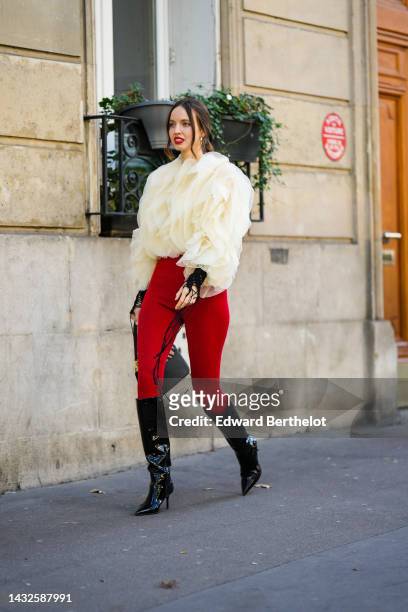 Guest wears gold earrings, a pale yellow ruffled tulle oversized blouse, red legging pants, a beige and black shiny leather zebra print pattern...