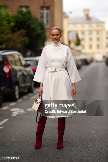 Guest wears diamonds earrings, a white latte turtleneck knees wool dress, a white belted coat jacket, a brown and beige leather bicolored Kelly...