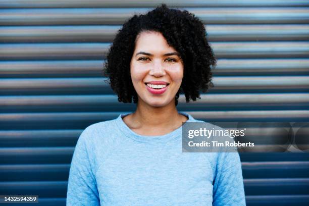 portrait of woman smiling with blue background - real life hero stock pictures, royalty-free photos & images