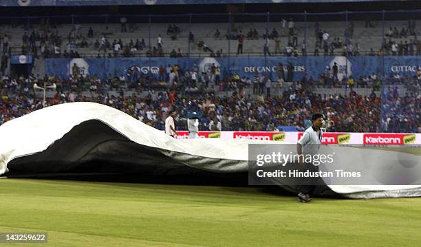 Crew pull tarps at the start of rain during the match between Deccan Chargers and Kolkata Knight Riders at Barabati Stadium on April 22, 2012 in...