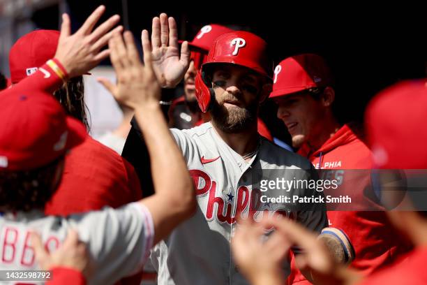 Bryce Harper of the Philadelphia Phillies celebrates in the dugout after scoring against the Atlanta Braves during the first inning in game one of...
