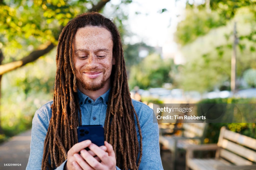 Man using smart phone next to trees