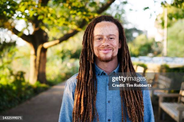 man looking at camera, next to trees - cabello rastafari fotografías e imágenes de stock