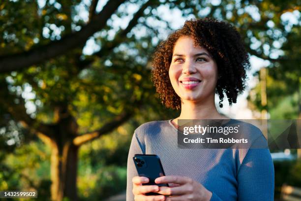 woman looking up using smart phone - date tree stock pictures, royalty-free photos & images