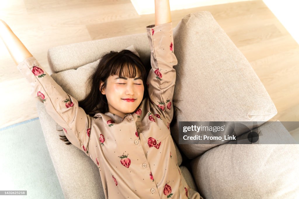 Junge Frau im Pyjama, die sich auf dem Sofa streckt