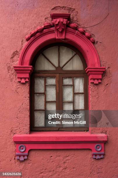 neo-classical-style, ornately carved stone pediment trim and sill on an arched window on the stucco exterior of an old building - window frame stock pictures, royalty-free photos & images