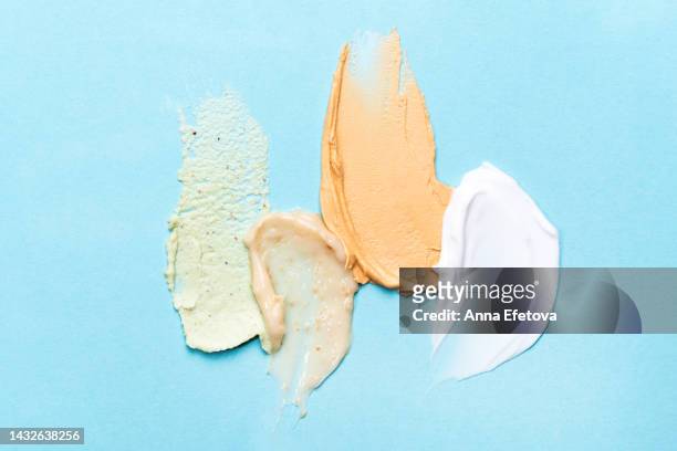 set of textured cosmetic smears smudged on blue background. moisturizing cream, exfoliating scrubs and cleansing facial mask. everything for your skincare and anti aging procedures. flat lay style - vitamins and minerals stock pictures, royalty-free photos & images