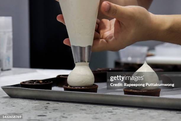 pastry chef finishing a delicious cream profiteroles - 菓子屋 ストックフォトと画像