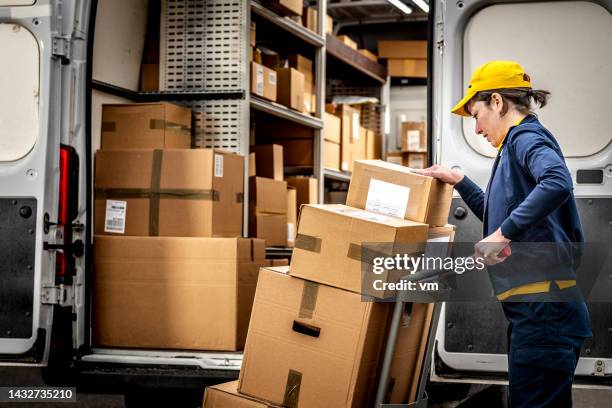 smiling courier loading hand truck, stacking packages - pick up truck stockfoto's en -beelden