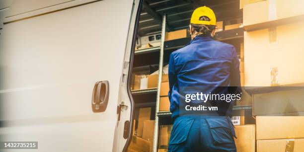 female courier in professional blue uniform unloading delivery truck, back view - pick up truck back stock pictures, royalty-free photos & images