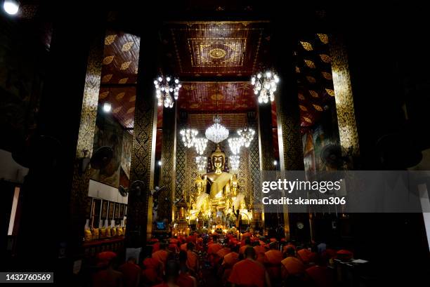 monks and buddhist come to pray for buddha   together in front of the golden big  buddha statue  at wat phra that hariphunchai  temple in lamphun province northern thailand - buddha purnima stock pictures, royalty-free photos & images