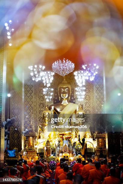 monks and buddhist come to pray for buddha   together in front of the golden big  buddha statue  at wat phra that hariphunchai  temple in lamphun province northern thailand - buddha purnima stock pictures, royalty-free photos & images