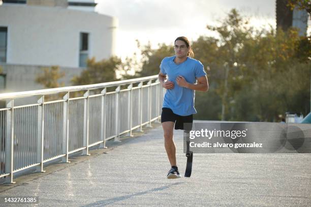 man with a prosthetic leg wearing sportswear while jogging outdoors. - piede artificiale per lo sport foto e immagini stock