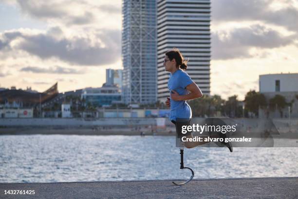 athlete man with a prosthetic leg jogging outdoors near the beach. - piede artificiale per lo sport foto e immagini stock