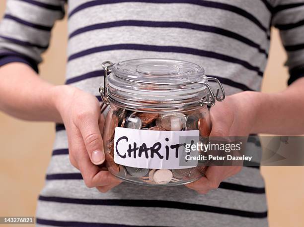 10 year old holding charity donations in a jar - charity and relief work stock pictures, royalty-free photos & images