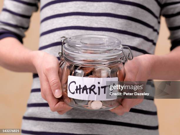 10 year old holding charity donations in a jar - philanthropy stock pictures, royalty-free photos & images