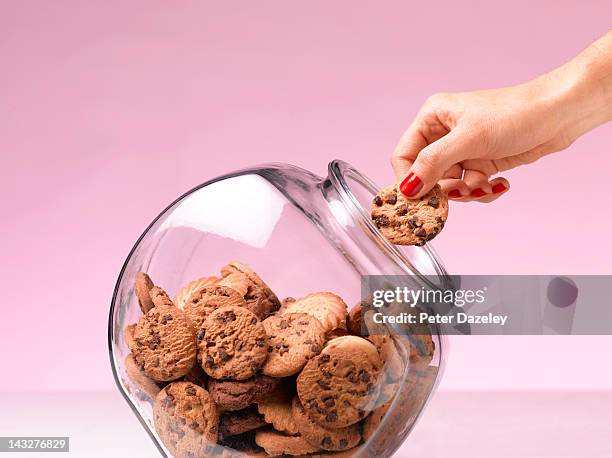 temptation - hand in a cookie jar - pot met koekjes stockfoto's en -beelden