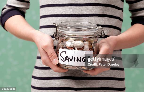 10 year old holding savings in jar - money jar stock-fotos und bilder