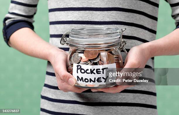 10 year old holding jar full of pocket money - zakgeld stockfoto's en -beelden