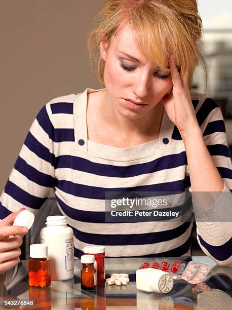 girl contemplating an array of perscription drugs - prescription drugs dangers stock pictures, royalty-free photos & images