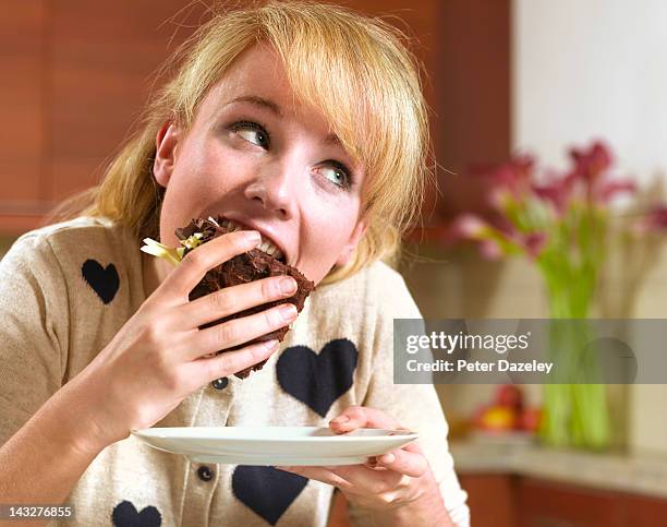 21 year old girl binge eating chocolate cake - avarice fotografías e imágenes de stock