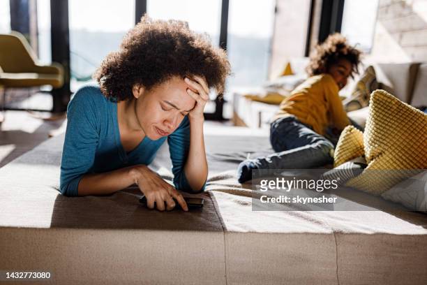 young black woman having a headache on sofa at home. - mom head in hands stock pictures, royalty-free photos & images