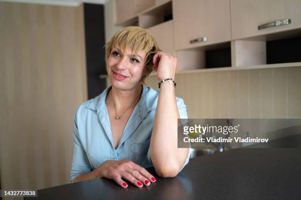 a portrait of a smiling transgender smiling into the distance while sitting at home - non binary stereotypes stock pictures, royalty-free photos & images
