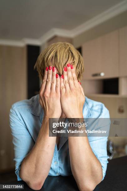 portrait of a transgender person holding both hands over his face while hiding it - pants down woman 個照片及圖片檔