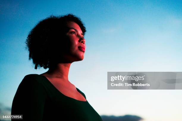 woman looking up, illuminated - licht von unten stock-fotos und bilder