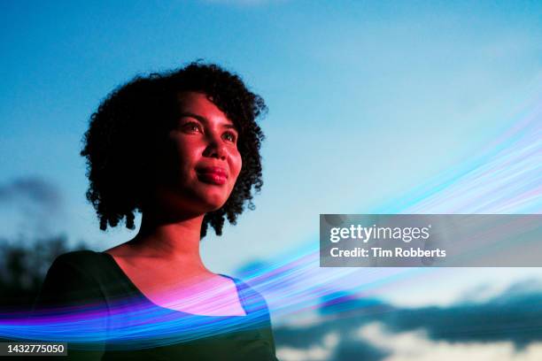 woman looking up with light streak - blurred and beautiful stock-fotos und bilder