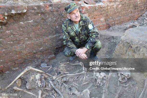 Volodymyr Kharchuk, sub of director director of the "Dolya" Memorial and Search Center, inspect excavated human remains at a common grave at the...