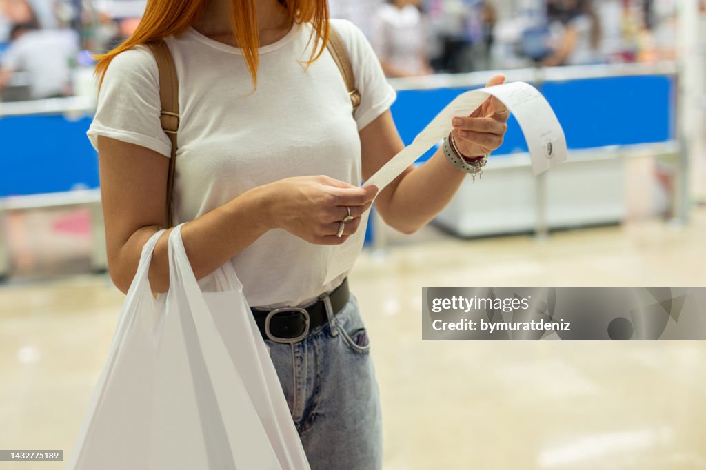 Women shopping at the supermarket and looks at receipt total